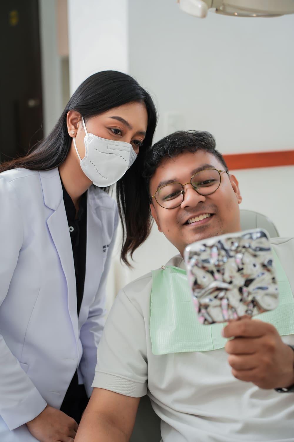 Patient smiling at his new smile in a hand mirror